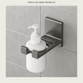 Adhesive wall bottle holder on grey bathroom tile holding a white pump bottle