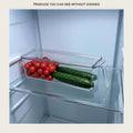 Clear lidded storage bin pulling forward on a fridge shelf with tomatoes and cucumbers