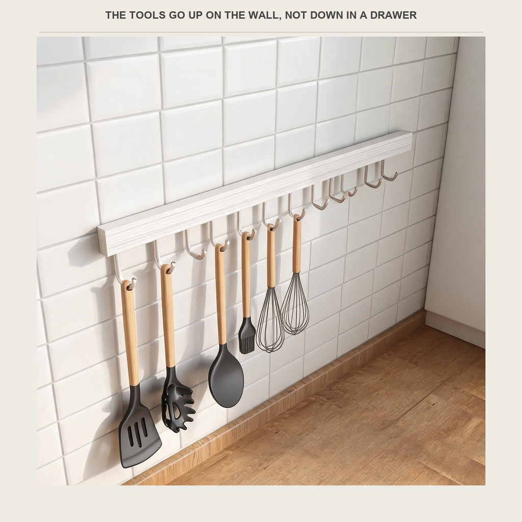 White kitchen utensil rail on a tiled splashback holding wooden handled cooking tools