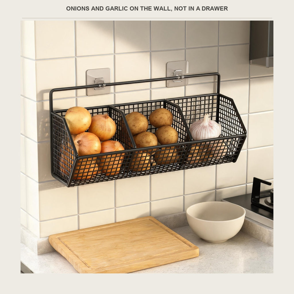Black wire wall basket with onions, potatoes and garlic in its three compartments above a kitchen counter