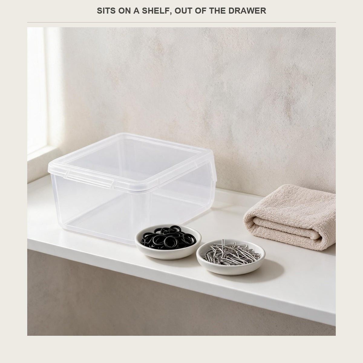 Hair accessory box sitting on a bathroom shelf beside small dishes of hair ties