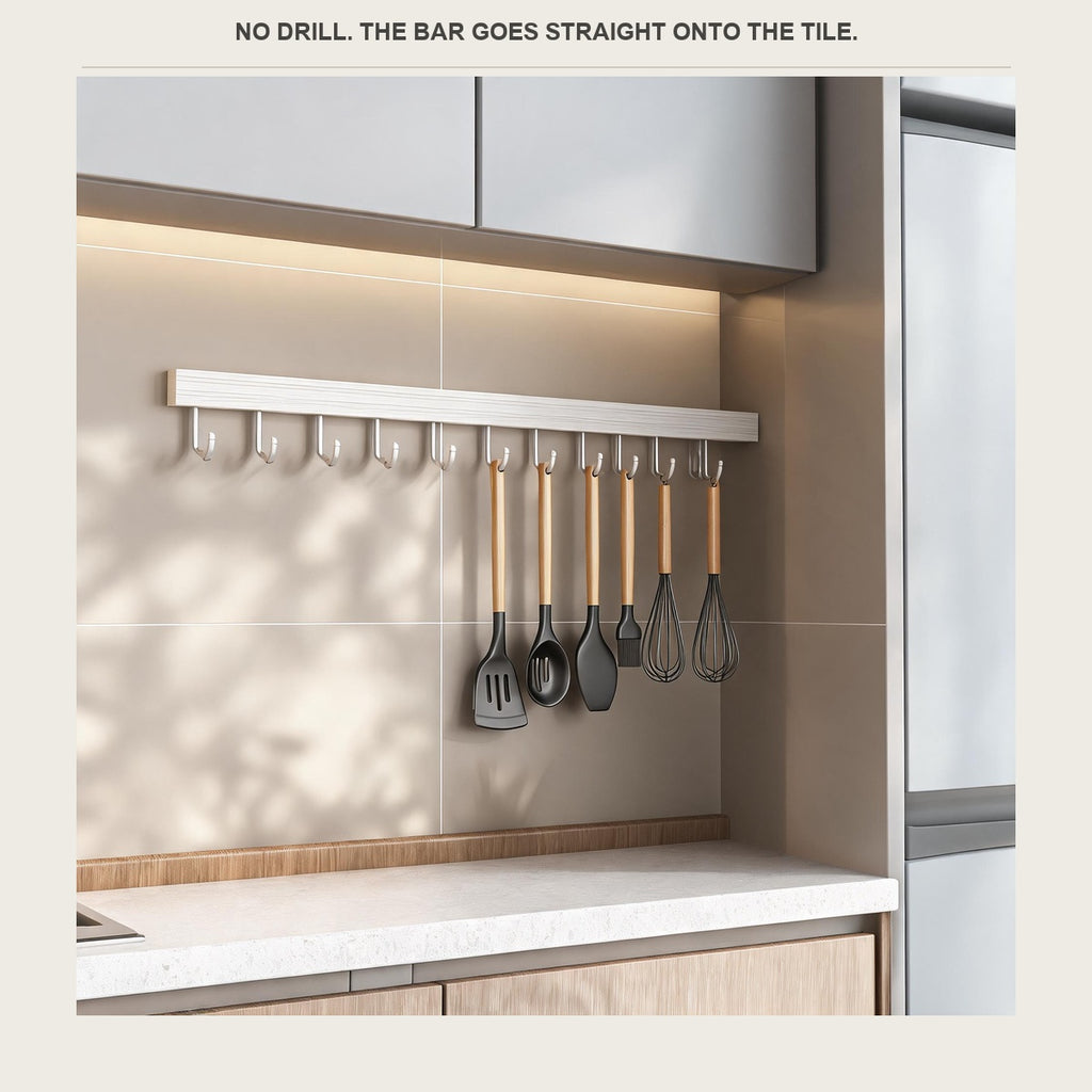 The utensil rail on a rental kitchen wall beside a fridge