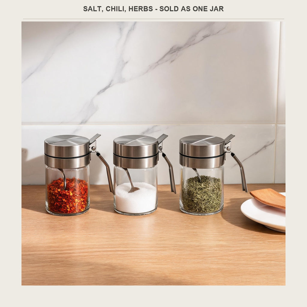 Three glass spice jars in a row holding chili flakes, salt and dried herbs