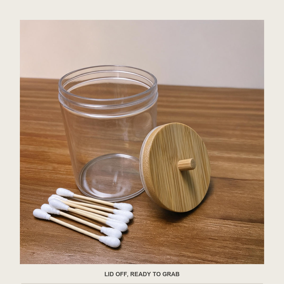 The acrylic jar open beside its bamboo lid on a wooden surface, with loose cotton swabs next to it