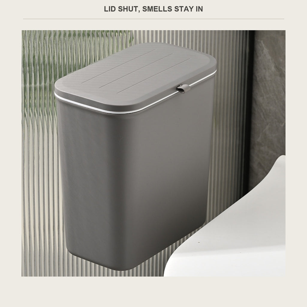 Grey hanging trash bin with the lid shut, mounted on a bathroom wall