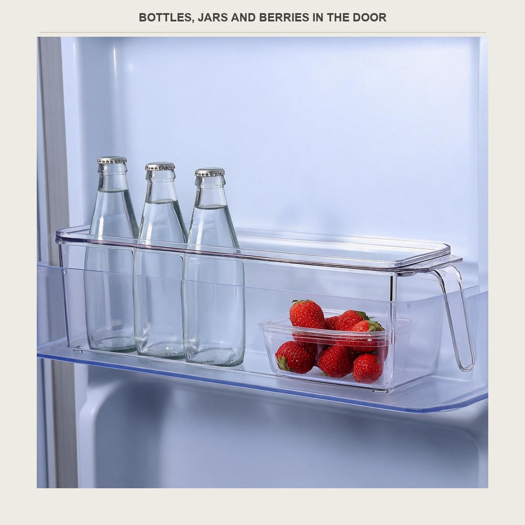 The clear bin in a fridge door holding small bottles and strawberries