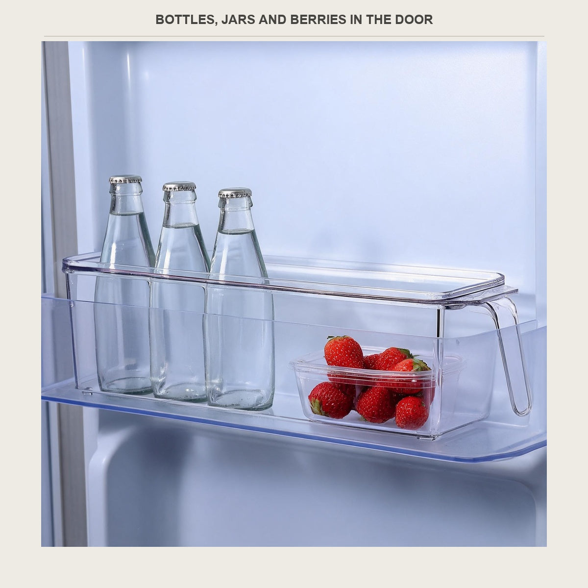 The clear bin in a fridge door holding small bottles and strawberries