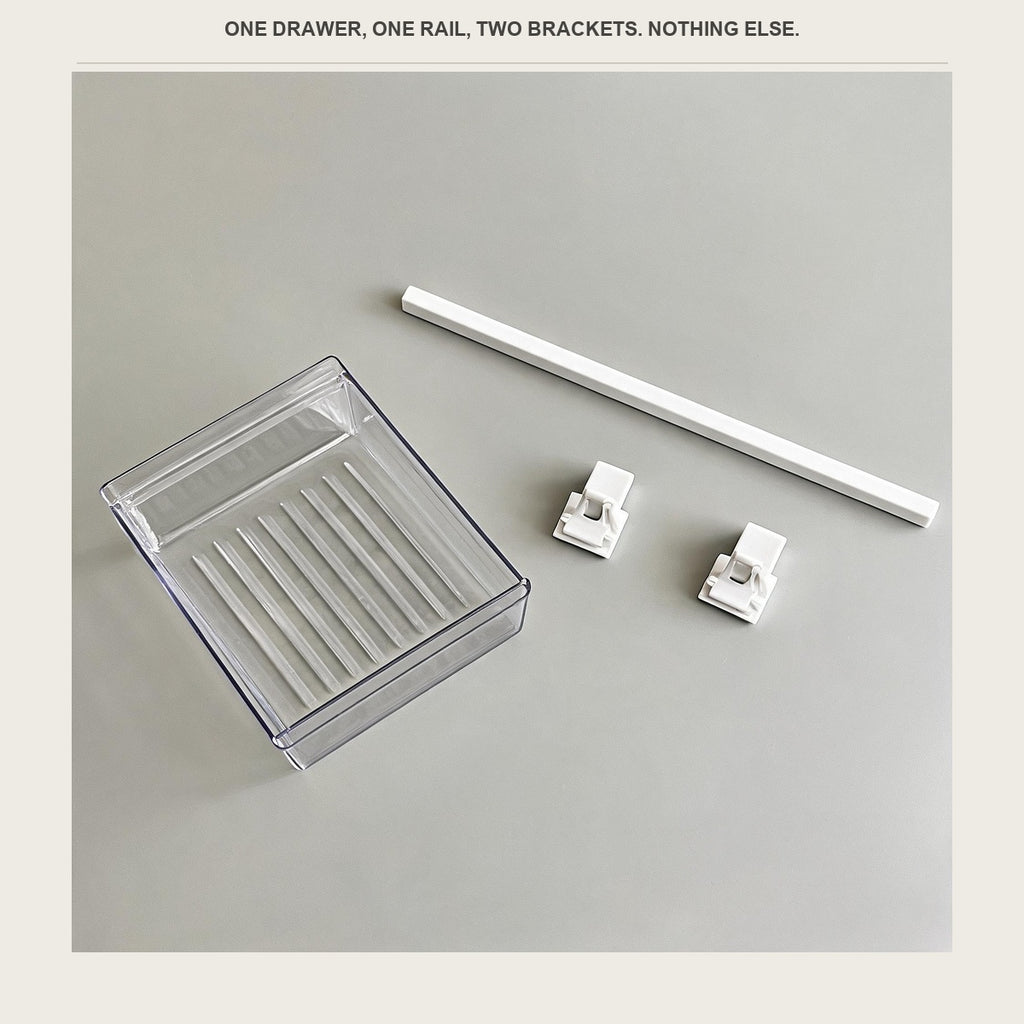 The clear drawer, the white rail and the two white brackets laid out on a pale surface