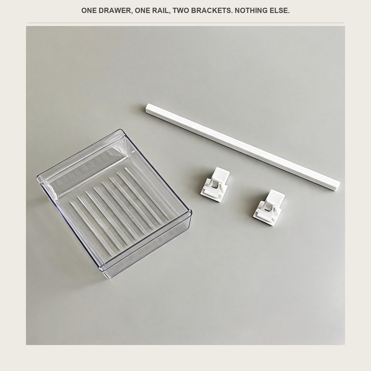 The clear drawer, the white rail and the two white brackets laid out on a pale surface