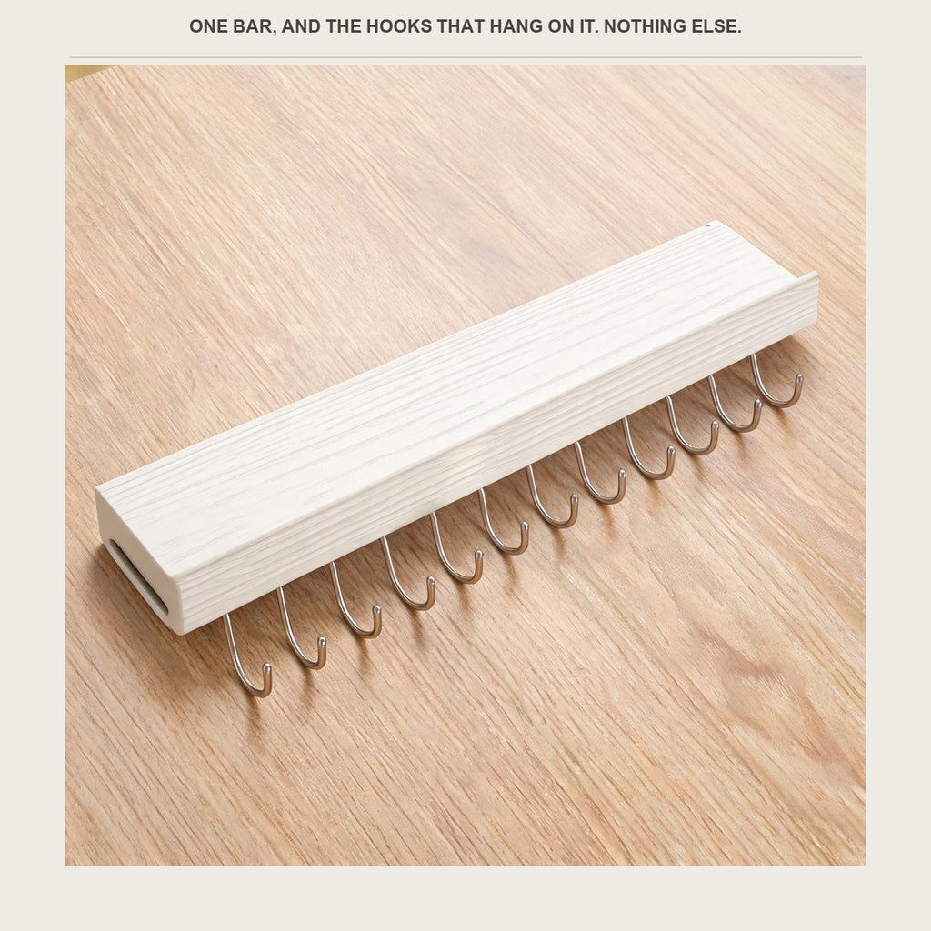 The utensil rail laid on a pale wood counter with its hooks beside it