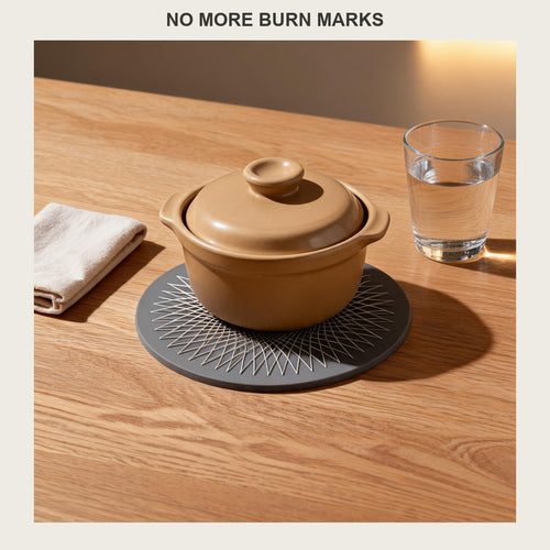 Round silicone trivet mat under a ceramic casserole dish on a light oak dining table