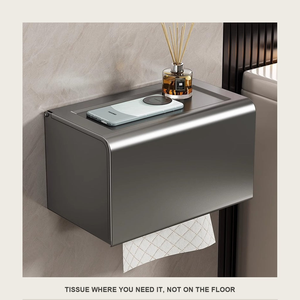 Wall mounted tissue box on a tiled bathroom wall with a phone and diffuser on top