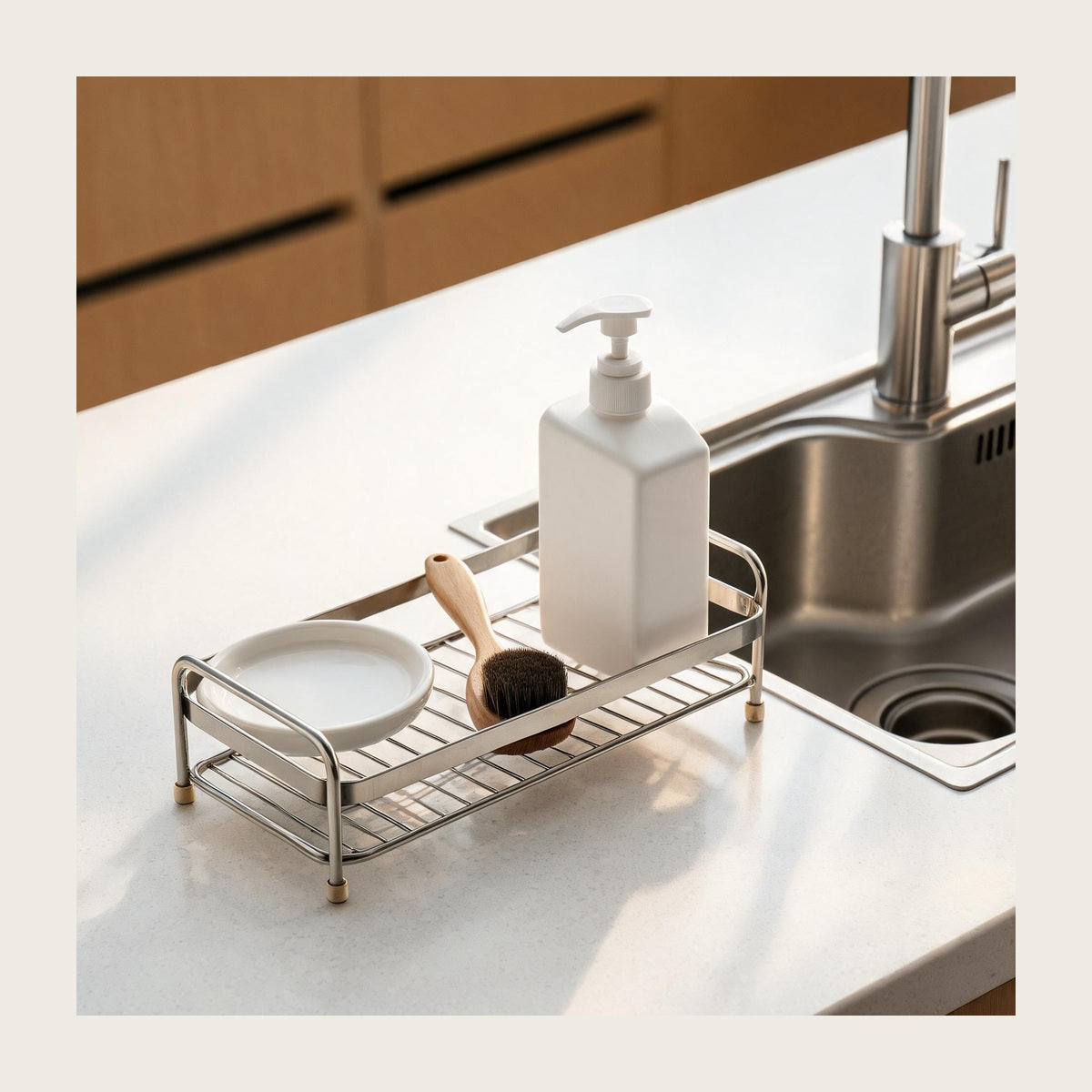 Silver stainless steel sink and vanity rack holding a soap dispenser and brush on a white kitchen countertop
