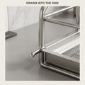 Narrow stainless steel dish drying rack with drain spout placed beside a kitchen sink