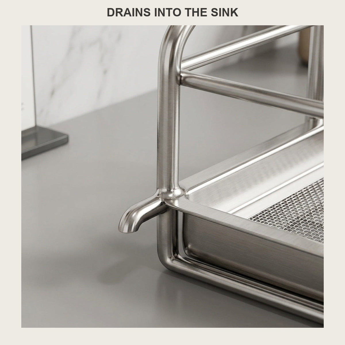 Narrow stainless steel dish drying rack with drain spout placed beside a kitchen sink