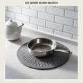 Round silicone trivet mat on a kitchen counter with a stainless pan resting on it